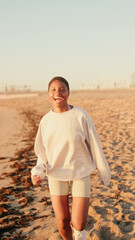 A girl in light colored casual clothes bouncing with happiness on the beach