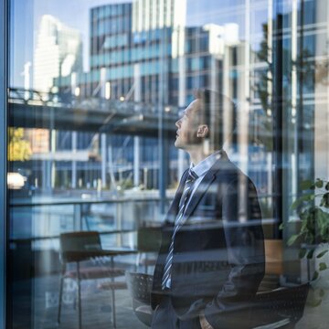 Candid Shot of a Worker Standing by a Large Window with Cityscape Reflection