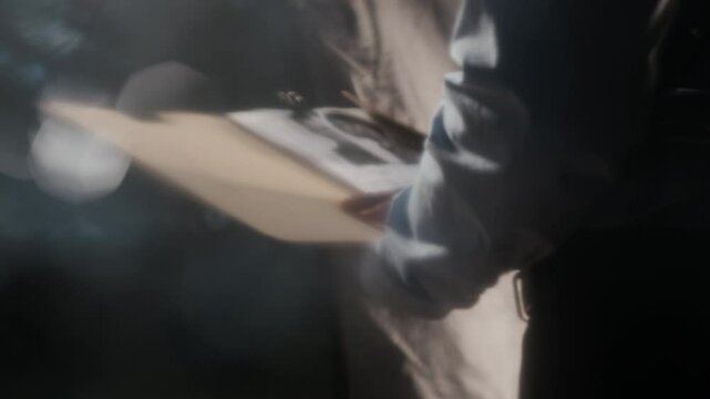 Cropped blurred shot of unrecognizable male police officer in uniform looking at criminal profile while working on case at night