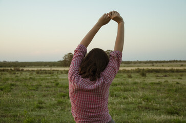 mujer contemplando un basto campo en un atardecer despejado