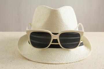 Straw hat with white rimmed sunglasses combination on table, front view of hat, beach hat, using accessories