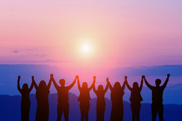 Silhouette of happy business teamwork making high hand over head standing in beautiful sunset  background for business success,.friendship,victory,cooperation,achievement,copy space.