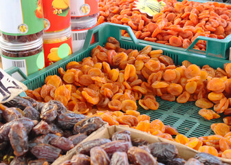 Dried fruits including apricot, plum, raisins, dates in the green baskets at the seasonal European market.