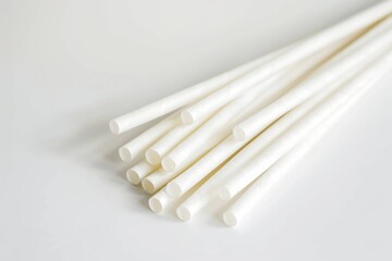 White paper straws arranged in a pile on a light surface. Eco-friendly and sustainability concept.