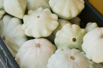 Light green patty pan squash in the blue basket sold at the seasonal autumn market among other vegetables.