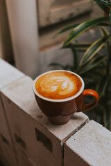 Cappuccino with beautiful foam in a red ceramic mug on a concrete background