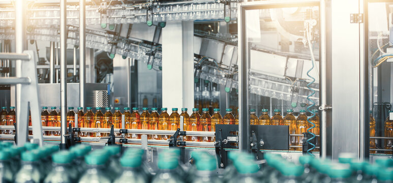 Bottling plant with conveyor line filled with plastic bottles for liquid packaging, industrial manufacturing and automation technology. Production process in modern factory.