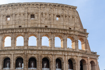 Fototapeta premium Rome, Italy - April 09, 2024: Ruins of the Coliseum with tourists strolling among the archaeological remains in Rome, Italy