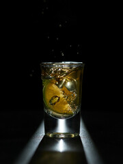 lemon falls into a glass of tequila, forming beautiful bubbles.