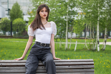 Young woman sitting on a bench in a summer park