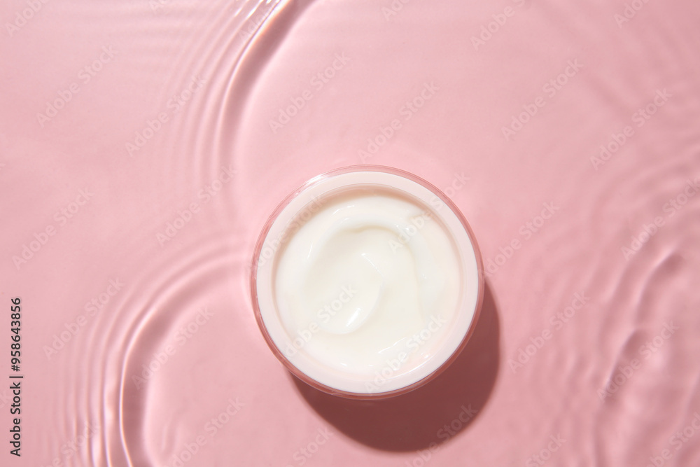 Wall mural cosmetic product. jar with cream in water on pink background, top view