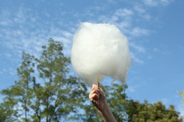 Little girl with sweet cotton candy against blue sky in park