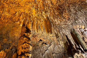 Cave wall with light, interior of the beautiful cave, abstract background and texture, stalactites and stalagmites, underground, natural water shaped walls