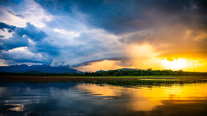Evening sun rays with rain clouds forming over Thap Salao Dam, Uthai Thani Province, Thailand.
