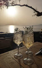 Two Hugo Spritz drinks in front of the sun setting over the Aegean Sea in Mykonos, Greece