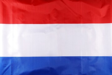 A close-up view of the national flag of Luxembourg featuring horizontal stripes of red, white, and blue colors, showcasing its vibrant design