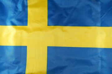 Swedish flag displaying bold blue and yellow colors proudly waving against a clear background...