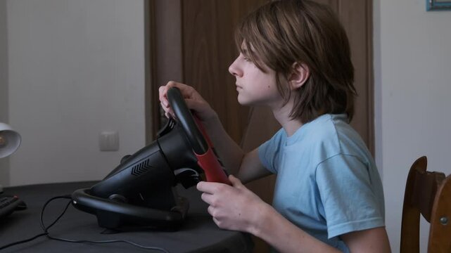 Boy is playing a video game with a wii remote or racing wheel