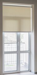 Beige roller blind is pulled down to cover a large glass door that leads to a balcony. The door is...