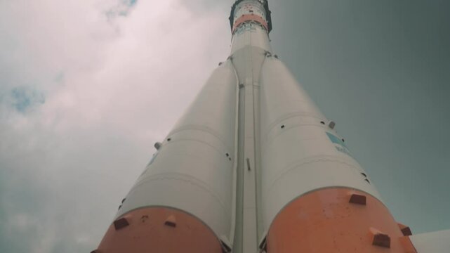 Vertical panorama of Soviet rocket on launchpad, pre-launch. Sleek steel body stretches from base to nose cone. Intricate details along entire length. Support structures visible at bottom.  sky backdr
