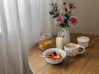 Delicious breakfast, snack - cornflakes with milk and fresh berries on a round wooden table