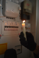 Checking the electricity power meter with a candle in cold winter days while there is power outage.