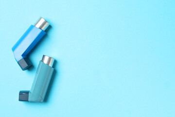 Naklejka premium Asthma inhalers on light blue background, flat lay. Space for text