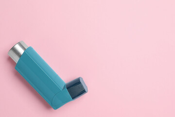 Asthma inhaler on pink background, top view. Space for text