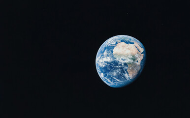Naklejka premium Earth viewed from space, surrounded by the black void, with visible continents, oceans, and clouds.