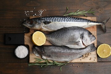 Sea food. Different types of raw fish, lemon and rosemary on wooden table, flat lay