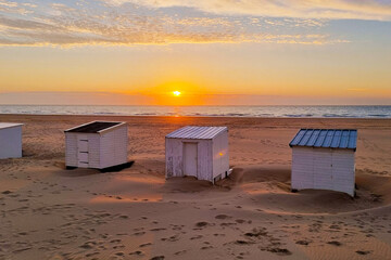 Tranquil Sunset Beach Scene with Three White Huts on Sandy Shoreline for Vacation Themes and Travel Design