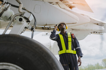 Mechanics inspect the engines of a large plane before takeoff at a summer airport..