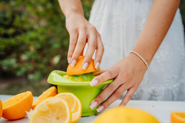 Close up of woman's hands using hand juicer for orange and lemon