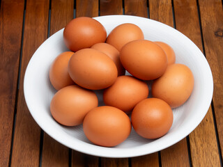 Huevos morenos de gallina en un bol sobre mesa de madera