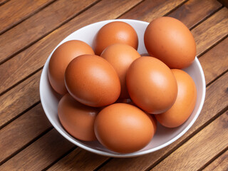 Huevos morenos de gallina en un bol sobre mesa de madera