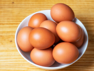 Huevos morenos de gallina en un bol sobre mesa de madera