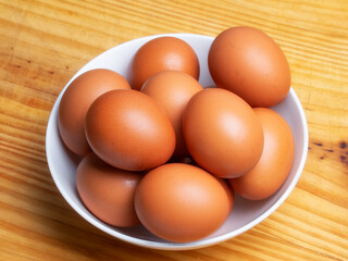 Huevos morenos de gallina en un bol sobre mesa de madera