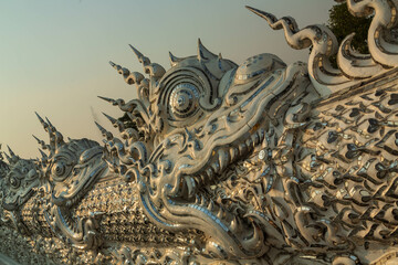 Chiang Rai, Thailand - March 2020: Part of the exterior of White temple or Wat Rong Khun. Close-up white and silver dragon 