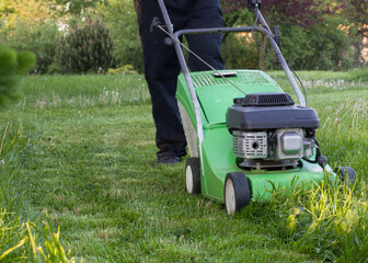 Fototapeta premium Man Mowing Grass with Green Lawn Mower