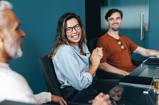 Business people smile happily as they discuss their latest success in a meeting