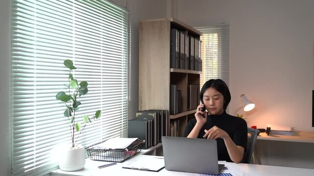 Asian businesses women working in the office used laptop and smartphone at her dest 