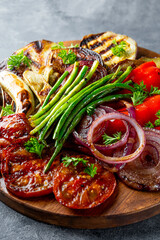 grilled vegetables - eggplant, pepper, onion, tomato and beans on grey background close up