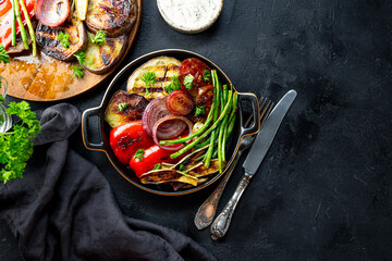 grilled vegetables - eggplant, pepper, onion, tomato and beans on black background top view