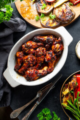 Baked chicken wings with teriyaki sauce and grilled vegetables on black background top view vertical photo