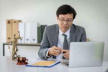 Portrait of mature asian notary public or lawyer working in the office,Male lawyer working at documents laptop in office.