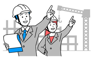 建設現場で資料を見ながら指示をするスーツの男女