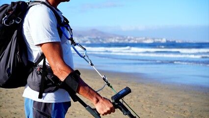 Naklejka premium Young man holding metal detector on beach. Close up of hand and arm of gold digger with electronic device searching for coins in sea