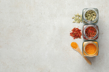 Different spices in glass jars on light grey table, flat lay. Space for text