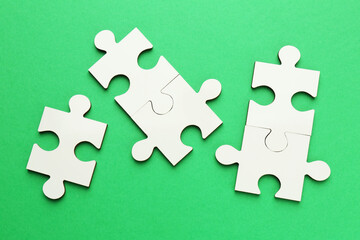 White puzzle pieces on green background, top view