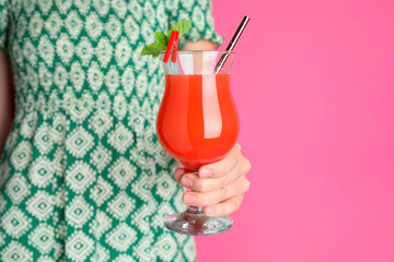 Woman with glass of refreshing cocktail on pink background, closeup. Space for text